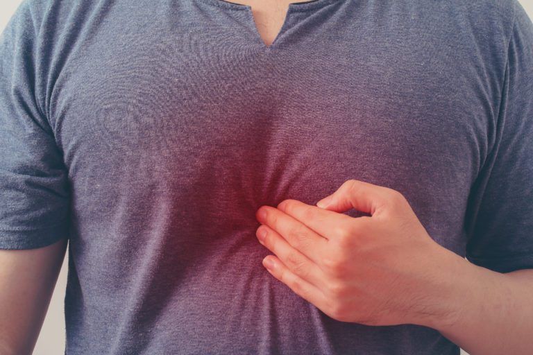 man holding chest from heartburn pain